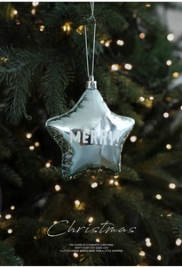 Close-up of blue star ornament with Merry Christmas lettering on a festive tree