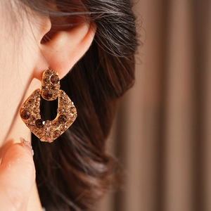 Gros plan de boucles d'oreilles vintage avec strass bruns portées par un mannequin