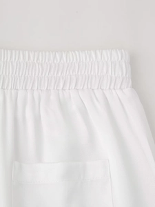 Detailed close-up of white woven elastic waistband and fine fabric texture of the trousers