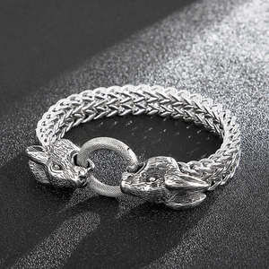 Macro detail of silver double-headed wolf viking bracelet on dark textured background