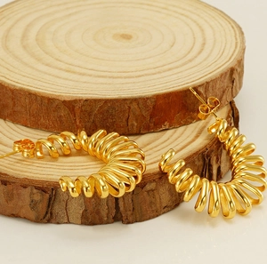 Gros plan détaillé de boucles d'oreilles spirales dorées sur support en bois