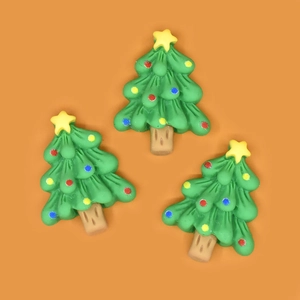 Detailed view of three resin Christmas tree charms with colorful ornaments on orange background