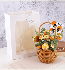 Detail of crochet orange gift basket with hand-woven flowers and white gift bag
