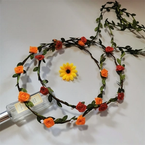 Detail of floral headband featuring red and orange fabric roses on brown vine base