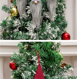 Detail of gray and red knitted Christmas gnomes hanging on a snowy festive tree branch
