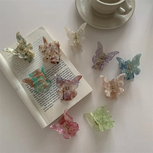 Elegant butterfly hair claws in marble and pearl acetate finishes on a white background