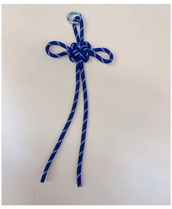 Close-up of a blue braided cord knot charm with a white pattern and silver metal ring