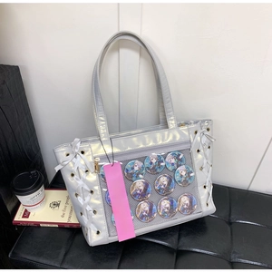 Close-up of silver ita bag with clear window, Genshin Impact badges, and lace detail