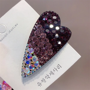 Macro shot of heart-shaped hair clip with purple gradient crystals on display card