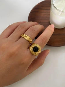 Detail of 18K gold open rings with natural black stone and hammered texture on hand