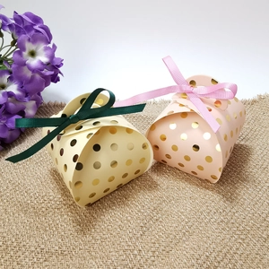 Detailed view of yellow and pink gift boxes with gold dots and satin ribbon bows