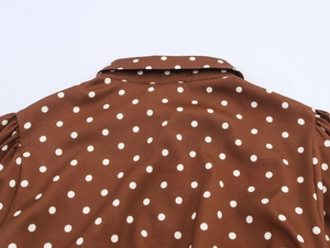 Detailansicht des weißen Punktmusters auf braunem Retro-Kleid mit Kragen und Faltenwurf