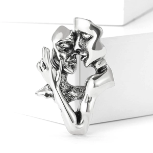 Detail of silver kissing lovers brooch on a white geometric block with artistic design