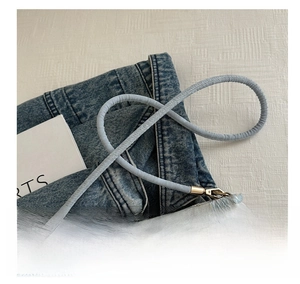 Detailed macro view of embroidered bucket bag featuring blue silk cord shoulder strap