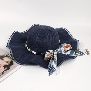 Detail of navy straw sun hat featuring a floral silk bow and white pearl accents