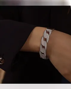 Detailed close-up of a silver Cuban link chain bracelet with textured engraved finish