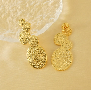 Detailed macro view of 18K gold plated titanium steel earrings with hammered lava texture