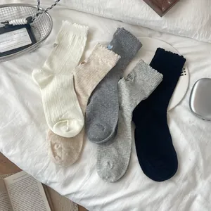Detail of five-color cotton crew socks with heart embroidery and ruffled edges in a basket