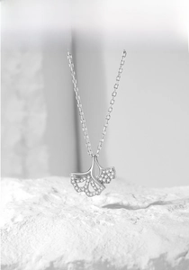 Detailed view of silver ginkgo leaf pendant encrusted with sparkling diamonds on chain