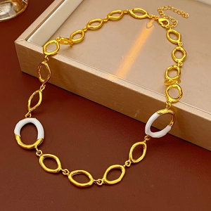 Detailed view of a gold chain necklace with oval links and white enamel accents