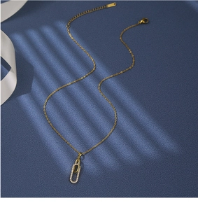 Détail du pendentif doré imbriqué serti de zircons sur un collier à chaîne en maille O