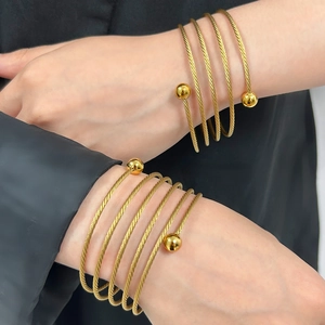 Bracciale a spirale dorato multistrato con perline indossato sul polso alla moda