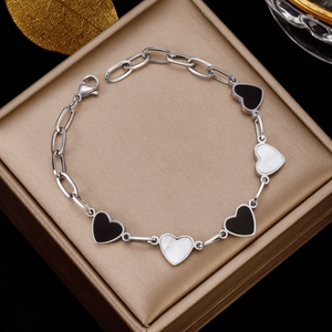 Detail of silver-tone clover bracelet with black and white heart charms on jewelry box