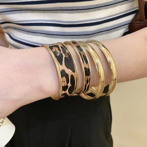 Close-up of stylish four-piece gold bracelet set featuring leopard print leather detail