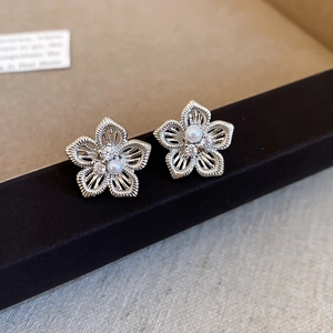 Makro-Detail von silbernen hohlen Blumenohrringen mit Perle und Zirkonia-Akzenten