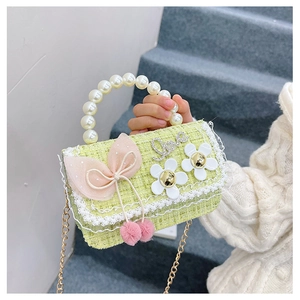 Detail of light green tweed kids bag with pearl handle, metal chain and pink bow decor