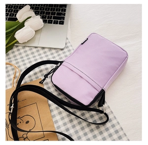 Detail view of purple textured fabric phone bag with front zipper and black strap
