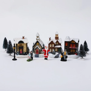 Miniature Christmas village set with glowing houses, Santa figures, and snowy pines