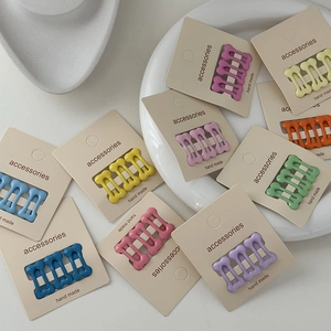 Set of colorful bone-shaped mini hair clips with polka dots on white ceramic tray