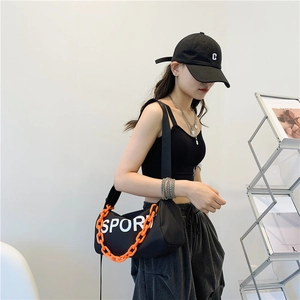 Sac bandoulière tendance en nylon noir avec chaîne orange et logo SPORT porté par un mannequin