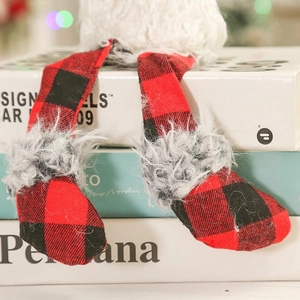 Close-up of Christmas gnome legs in red black plaid fabric sitting on books