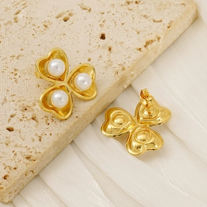 Macro detail of 18K gold-plated clover stud earring with three white pearls on silk fabric