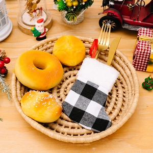 Detail of buffalo plaid Christmas stocking utensil holder with gold cutlery on rustic wood
