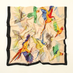 Detailed close-up of silky satin scarf featuring vibrant parrot prints and black borders