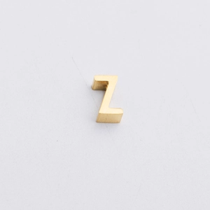 Macro detail of golden stainless steel letter Z bead with a polished brushed texture