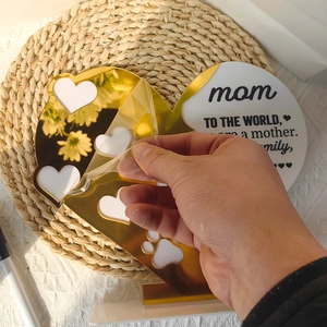 Hand peeling protection film from gold mirror acrylic heart plaque for Mother's Day