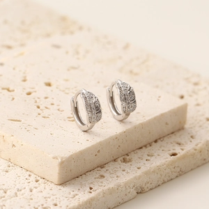 Gros plan de boucles d'oreilles feuilles en argent avec zircons sur pierre texturée