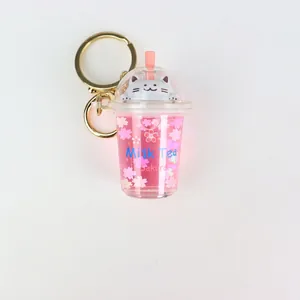 Pink milk tea cup acrylic keychain with floating cherry blossoms and cute cat topper