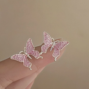 Close-up of pink enamel butterfly earrings with silver-toned hollow wing details