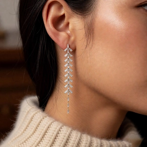 Close-up of silver tassel earrings with baguette-cut cubic zirconia in a leaf pattern