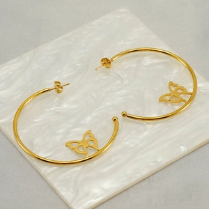 Gold stainless steel hoop earrings featuring hollow butterfly charms on marble