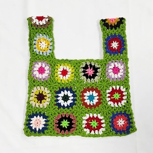 Detailed view of hand-crocheted green bag with colorful floral embroidery patterns