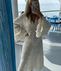 Detail of V-neck crochet lace dress featuring bell sleeves and intricate patterns