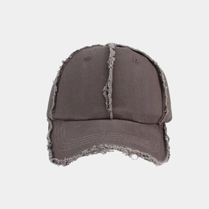 Detail of distressed raw edges and vintage canvas texture on a dark brown baseball cap