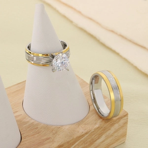 Close-up of two-tone stainless steel rings with brushed texture and large crystal