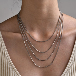 Close-up of minimalist silver snake bone chain layered on a neck for a chic style